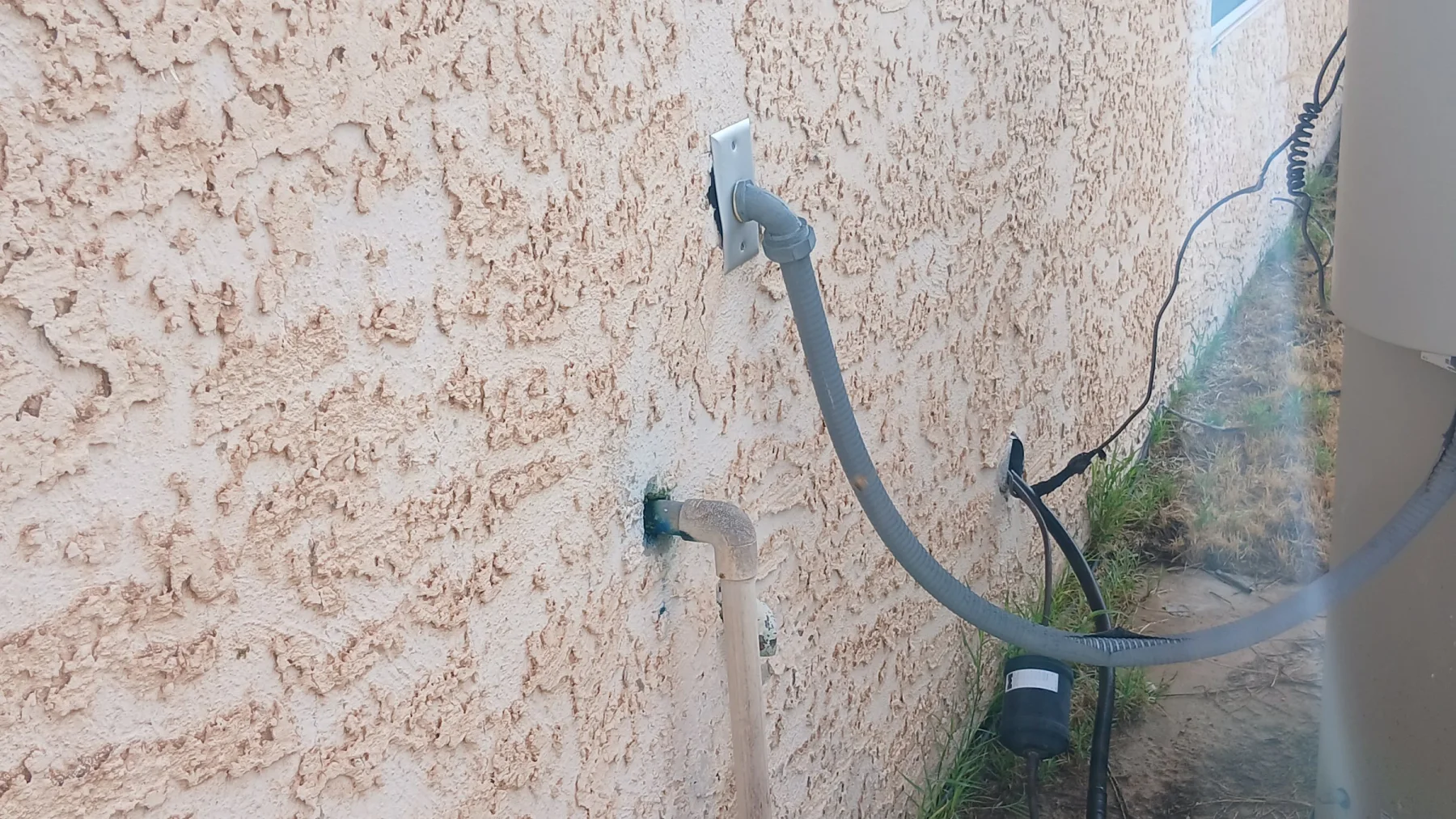 Bee inspection of stucco wall in Mohave Valley, with bees entering and exiting a plumbing penetration